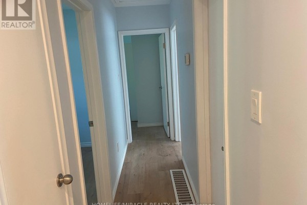 Hallway with light wood flooring, light blue walls, and doors leading to rooms. - Main Floor - 25 Thornridge Crescent, Kitchener