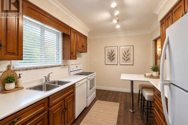 Kitchen with white appliances, double sink, wood cabinets, and a small breakfast bar. - Main Floor - 37 Downsview Drive, Barrie
