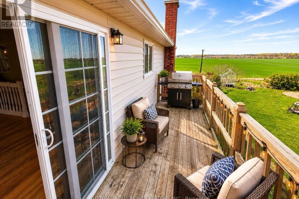 Backyard with a wooden fence, fire pit area with chairs, and a view of open green fields. - Main Floor - 62 Laidlaw Drive, Barrie