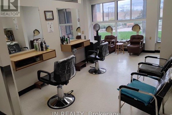 Hair salon with styling chairs, hair dryers, and windows overlooking greenery. - Main Floor - 7900 Mclaughlin Road, Brampton