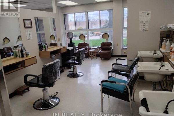 Styling chairs and hair dryers in a salon, with sinks visible. - Main Floor - 7900 Mclaughlin Road, Brampton