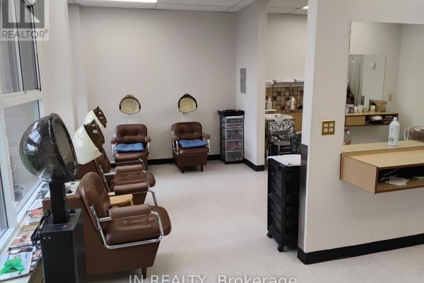 Hair salon seating area with hair dryers and sinks near large windows. - Main Floor - 7900 Mclaughlin Road, Brampton