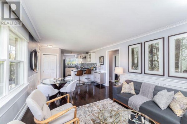 Open concept living and dining area with a kitchen island, bar stools, and view into hallway. - Main Floor Apartment - 438 Third Line, Oakville