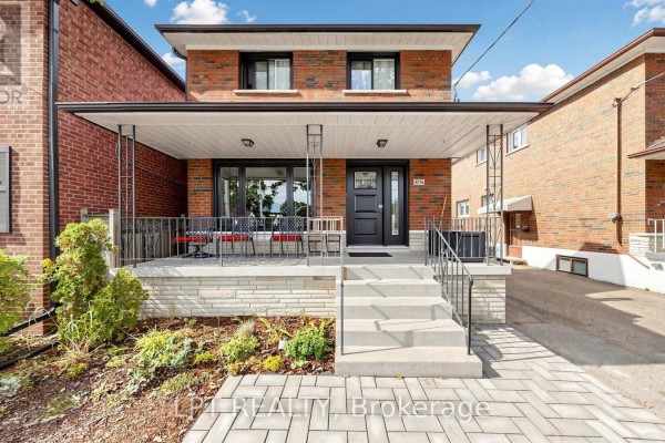 Front porch of a brick house with seating, black railings, and stone base. - Main Floor Apt. - 477 Cosburn Avenue, Toronto
