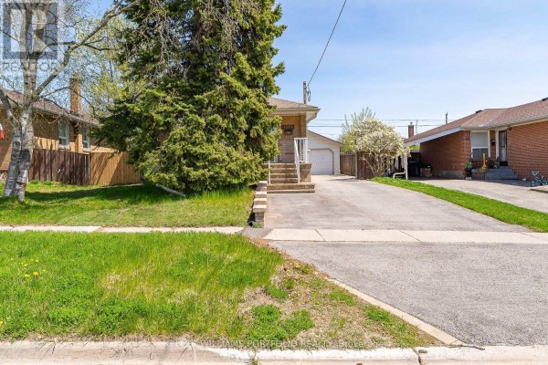 View of the house from the left side, showing the lawn, driveway, and neighboring properties. - Main Flr - 1519 Lakeside Street, Oshawa