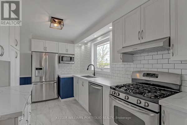 Kitchen view showing white subway tile backsplash, stainless steel appliances, gas range, and white cabinetry with white countertops. - Main Flr - 1519 Lakeside Street, Oshawa