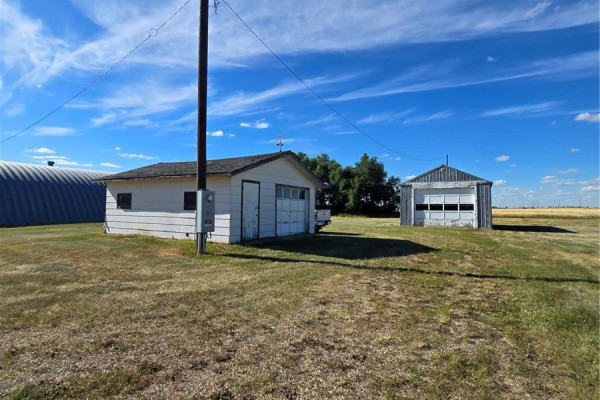 Two detached garages with corrugated metal siding and rolling doors in a grassy yard. - Mccormick Acreage, Weyburn Rm No  67