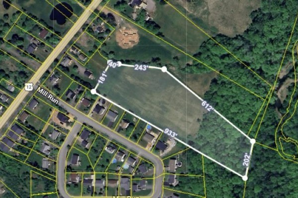 Aerial view of a residential neighborhood surrounded by greenery and open land. - Mill Run Extension Extension, Kentville