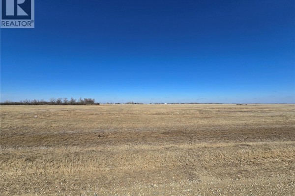 Wide view of a dry grassy field with distant trees under a bright blue sky. - Minards South Lot 7, Weyburn Rm No  67