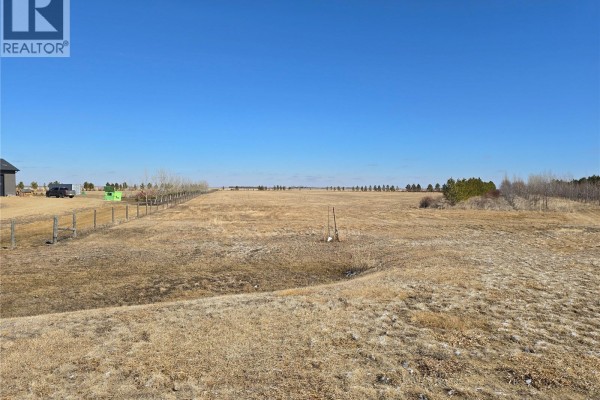 Open field with scattered trees, fences, and a pond under blue sky. - Minards South Lot 8, Weyburn Rm No  67