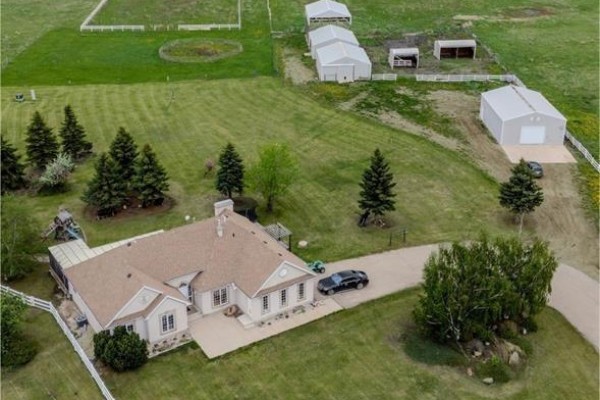 Overhead view of the beige house on a large lot with outbuildings and mature trees. - Misty Lane Acreage, Orkney Rm No  244