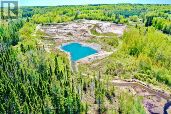 Aerial view of a quarry with a blue lake and surrounding forest and water bodies. - Moonbeam - 187-a Ouellette Bay Road, Kapuskasing