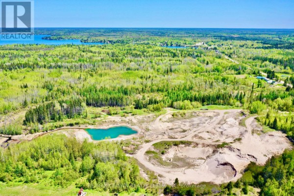 Distant aerial view of a large quarry and lake nestled within a vast, tree-covered landscape. - Moonbeam - 187-a Ouellette Bay Road, Kapuskasing