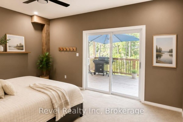 Primary bedroom with a large sliding glass door opening onto a wooden deck with a barbecue. - 157 Desroches Trail, Tiny