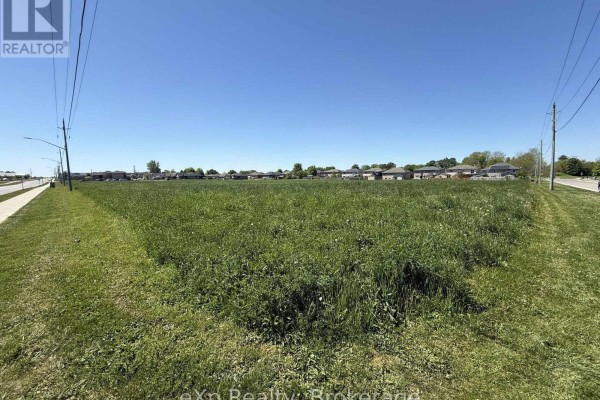 Wide view of a vast, green, overgrown lot bordered by a sidewalk, road, and residential homes under a clear blue sky. - N/a 18th Avenue, Hanover