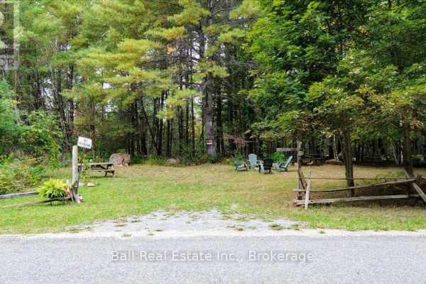 Cleared grassy area with picnic table, chairs, and a rustic wooden fence, surrounded by trees. - N/a Coon Lake Road, North Kawartha