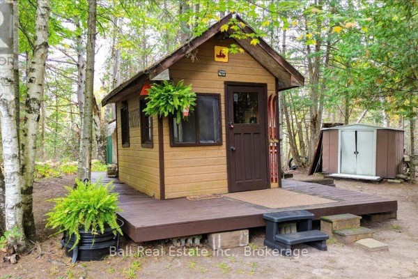 Small wooden cabin with a brown door, wooden deck, and a window surrounded by trees. - N/a Coon Lake Road, North Kawartha