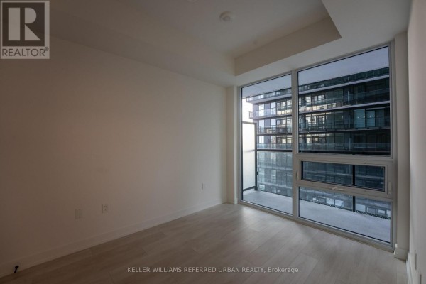 Empty room with large windows and balcony doors showing a view of a modern building exterior. - N1301 - 117 Broadway Avenue N, Toronto