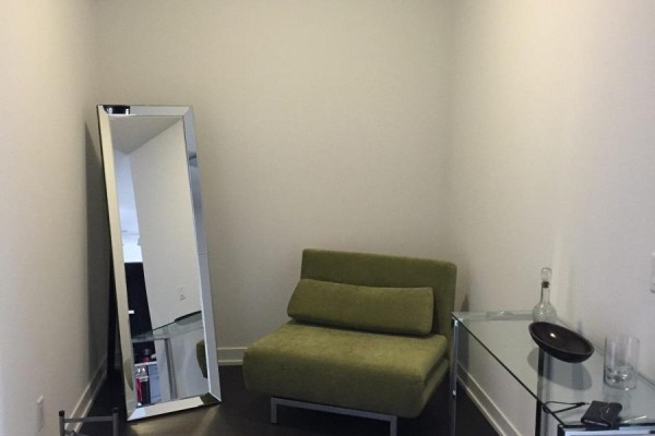 Small seating area with a green accent chair, large mirror, and glass side table. - N222 - 120 Bayview Avenue, Toronto