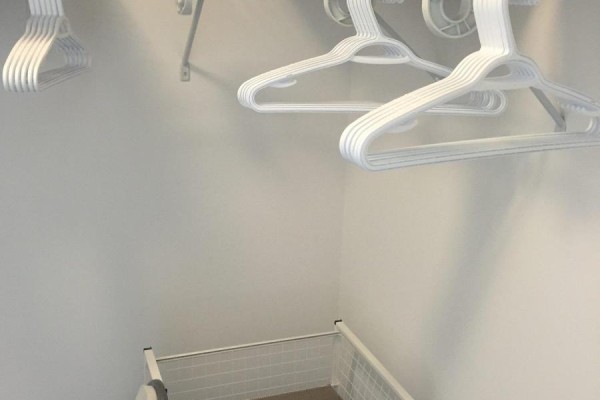 Interior view of a closet with white clothing hangers and a storage bin. - N222 - 120 Bayview Avenue, Toronto