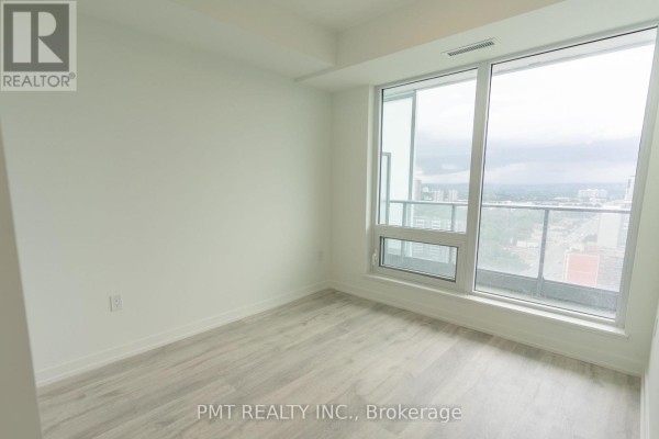 Bedroom with light wood floors and a large window offering panoramic views of the city skyline. - N2610 - 7 Golden Lion Heights, Toronto