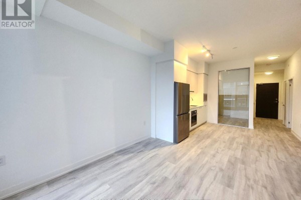 View of the living area and modern kitchen with a glass-door entryway visible. - N625 - 7 Golden Lion Heights, Toronto