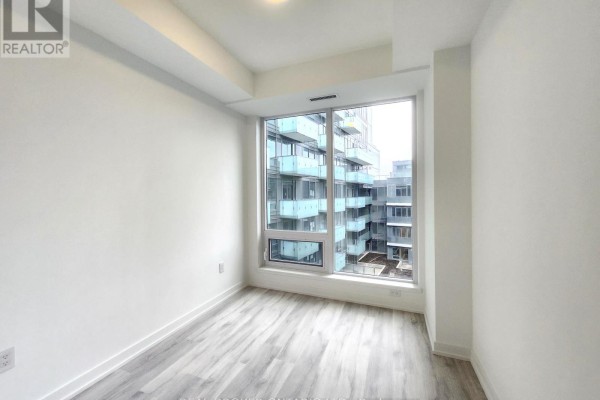 Bedroom with a large window overlooking a building with balconies. - N625 - 7 Golden Lion Heights, Toronto