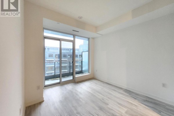 Bedroom with sliding glass doors leading to a balcony, overlooking an adjacent building. - N625 - 7 Golden Lion Heights, Toronto