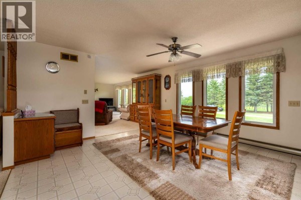Dining area with a wooden table and chairs, china cabinet, and large windows overlooking fields. - Ne 19-47-23-w3 Rm Eldon, Maidstone