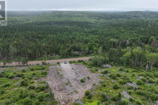 Aerial view of a cleared section of land with an excavator, leading to a paved road and dense forest. - New Boston Road, Catalone River