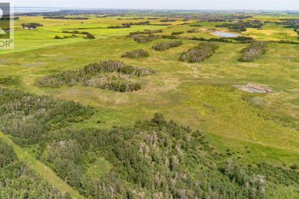 Wide aerial shot of a vast green landscape with trees, fields, and a small pond. - On Range Rd 215, Rural Stettler No  6, County Of