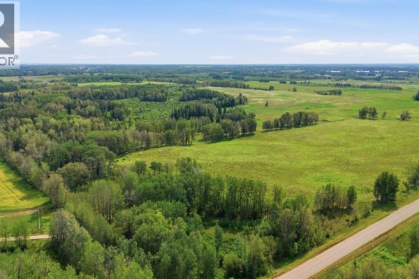 Overhead view of a farm property with fields, trees, and a paved road under a daytime sky. - On Range Road 45, Rural Clearwater County