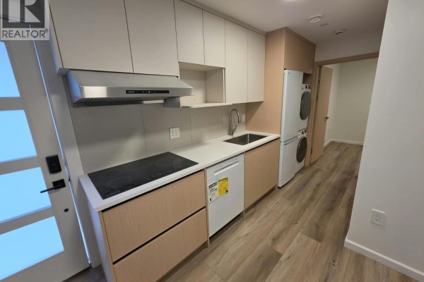 Close-up of the kitchenette featuring a sink, stovetop, dishwasher, and modern cabinetry. - One Bedroom Basement-xx W 63 Avenue, Vancouver