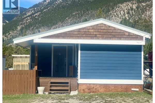 Wooden fence in the foreground with grassy field and pine trees leading to a mountain. - Pad #14 - 5174 Lambert Road, Invermere