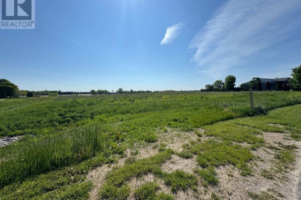Large, undeveloped grassy field with a dirt path on the right, under a sunny blue sky. - Part 7 Fullerview Drive, Central Huron