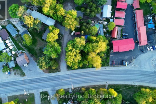 Aerial view showing multiple structures including homes, motel, and green space, bordered by a road. - Part Lot 99 Lakeshore Drive, North Bay