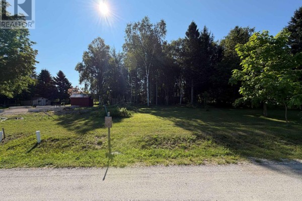 A sunny, grassy lot with trees bordering a paved road in a residential area. - Parts 3 & 4 Kovac Lane, Saugeen Shores