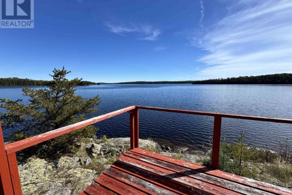 View from the cottage deck overlooking a calm blue lake surrounded by evergreen trees. - Pcl 8 Sec Dog Lk, District Of Algoma