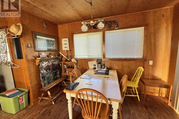 Interior view of a cottage dining area with a wooden table, chairs, and wood-paneled walls. - Pcl 8 Sec Dog Lk, District Of Algoma