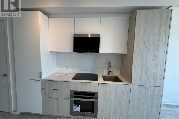 Close-up of a modern kitchen with white and light wood cabinetry, stainless steel appliances, and white tiled backsplash. - Ph04 - 28 Eastern Avenue, Toronto