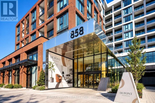 Close-up exterior view of the "858 Dupont" condo building entrance with glass and mirrored accents. - Ph04 - 858 Dupont Street, Toronto