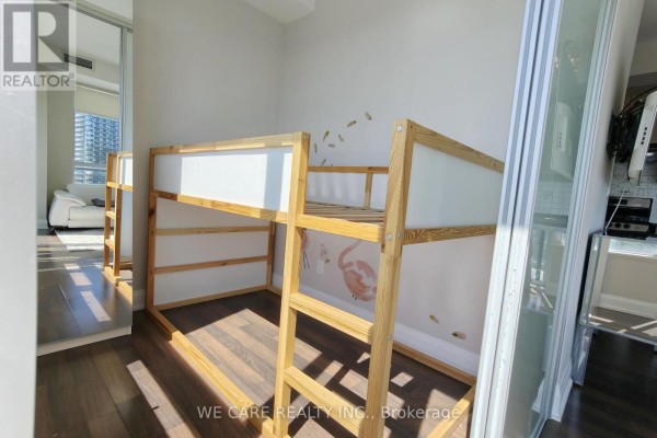 Bunk beds with wooden frames in a room with light walls and hardwood floors. - Ph05 - 68 Canterbury Place, Toronto