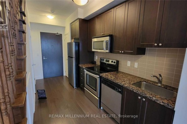 A compact kitchen with dark wood cabinets, granite countertops, stainless steel appliances, and a tiled backsplash. - Ph08 - 1060 Sheppard Avenue, Toronto