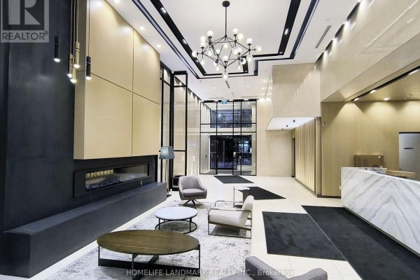 Apartment building lobby with a linear fireplace, contemporary furniture, and marble reception desk. - Ph09 - 1 Belsize Drive, Toronto