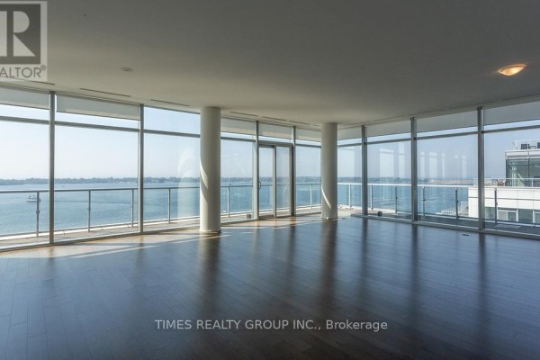 Spacious living room with floor-to-ceiling windows, dark wood floors, and water view. - Ph1203 - 39 Queens Quay E. Street E, Toronto