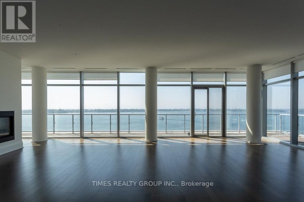 Large open-concept living area with a fireplace, dark wood floors, and panoramic water views. - Ph1203 - 39 Queens Quay E. Street E, Toronto