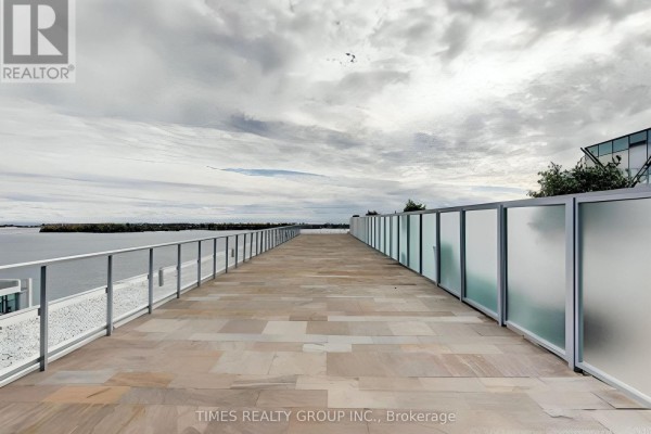 Spacious terrace with stone pavers and glass railings overlooking a body of water. - Ph1302 - 39 Queens Quay E. Street E, Toronto