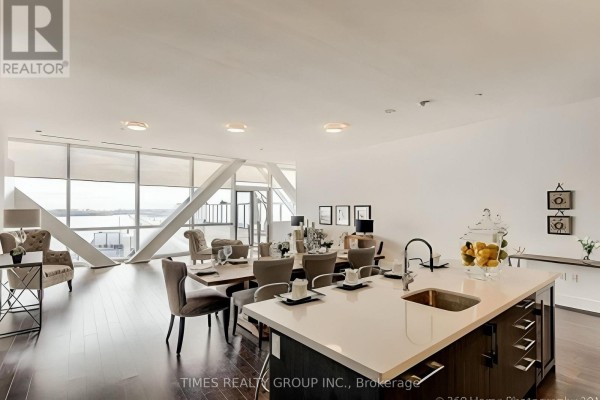 Open concept living and dining area with large windows, a kitchen island, and contemporary furniture. - Ph1302 - 39 Queens Quay E. Street E, Toronto