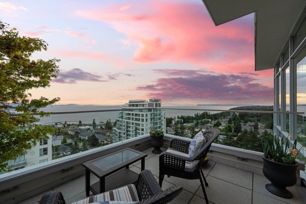 Balcony with seating area overlooking the ocean and cityscape at sunset. - Ph2 1473 Johnston Road, White Rock
