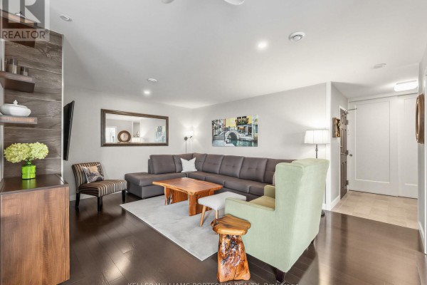 Living room with sectional sofa, fireplace, accent chairs, wooden coffee table, and artwork. - Ph208 - 2 Westney Road N, Ajax